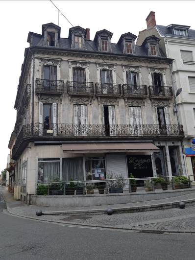 Immeuble ancien de 3 étages avec une façade grise, avec un magasin en rez-de-chaussée, avant sa rénovation