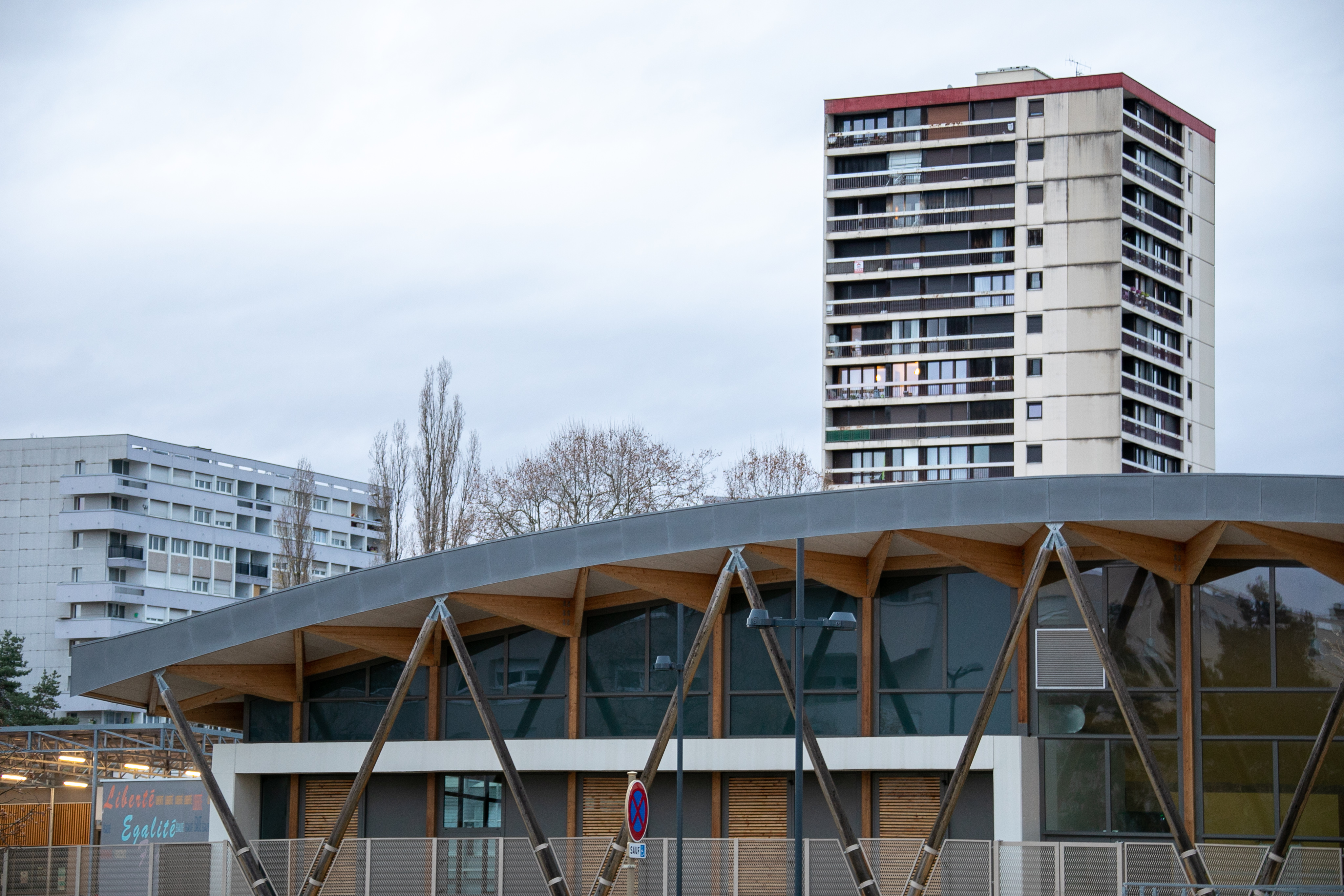 A Besançon, dans un quartier prioritaire, vue sur la halle d'un nouvel équipement sportif, acec en second plan une tour d'habitation ancienne.