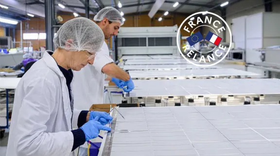 Vue de 2 personnes en blouses blanches et charlotte sur la têtre qui travaillent sur une plaque blanche, dans une industrie 