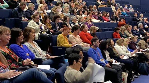 Des personnes assises dans un amphithéâtre écoutent une conférence.