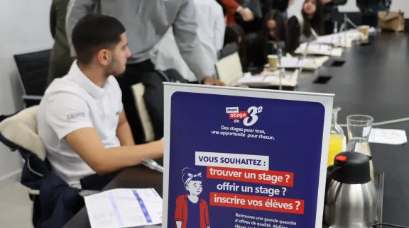 Les stagiaires accueilis en stage sont autour d'une grande table, en réunion, avec leurs tuteurs et tutrices.