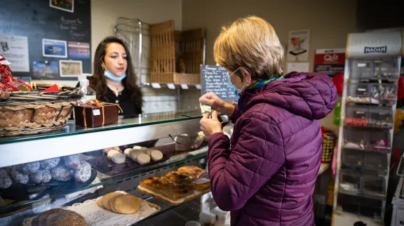 Commerçante derrière son comptoir d'épicerie face à une cliente