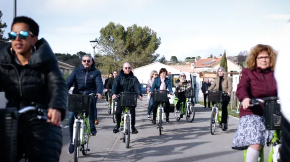 Groupe de personnes adultes à vélos électrique, dans la rue d'un lotissement.