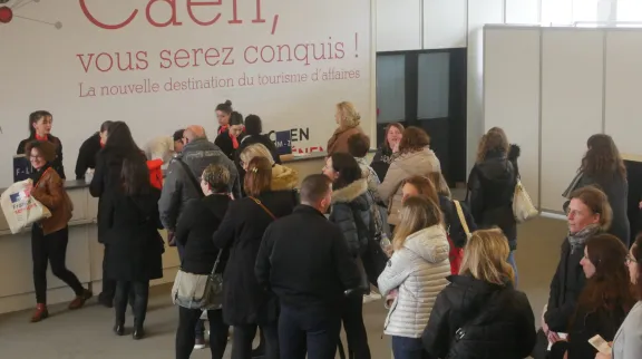 Des gens font la queue pour s'enregistrer à l'accueil d'un événement.